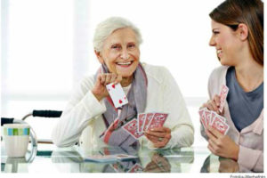 Junge und ältere Dame beim Kartenspielen.