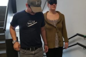 Zivildiener führt eine Person mit Dunkelbrille