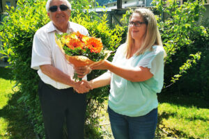 Klaus Guggenberger überreicht Sabine Karrer einen Blumenstrauß
