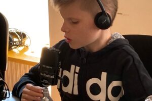 Serafin sitzt im Besprechungsraum am Tisch und testet das mobile Aufnahmegerät, mittels Sprechproben