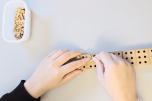 Das Bild zeigt zwei Damen-Hände mit dem Braillesteckbrett