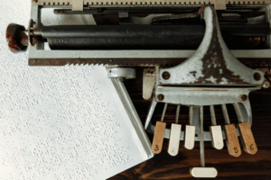 Detailaufnahme einer historischen Braille-Schreibmaschine und Braillepapier als Symbol für 200 Jahre Brailleschrift; Foto: Pexels.